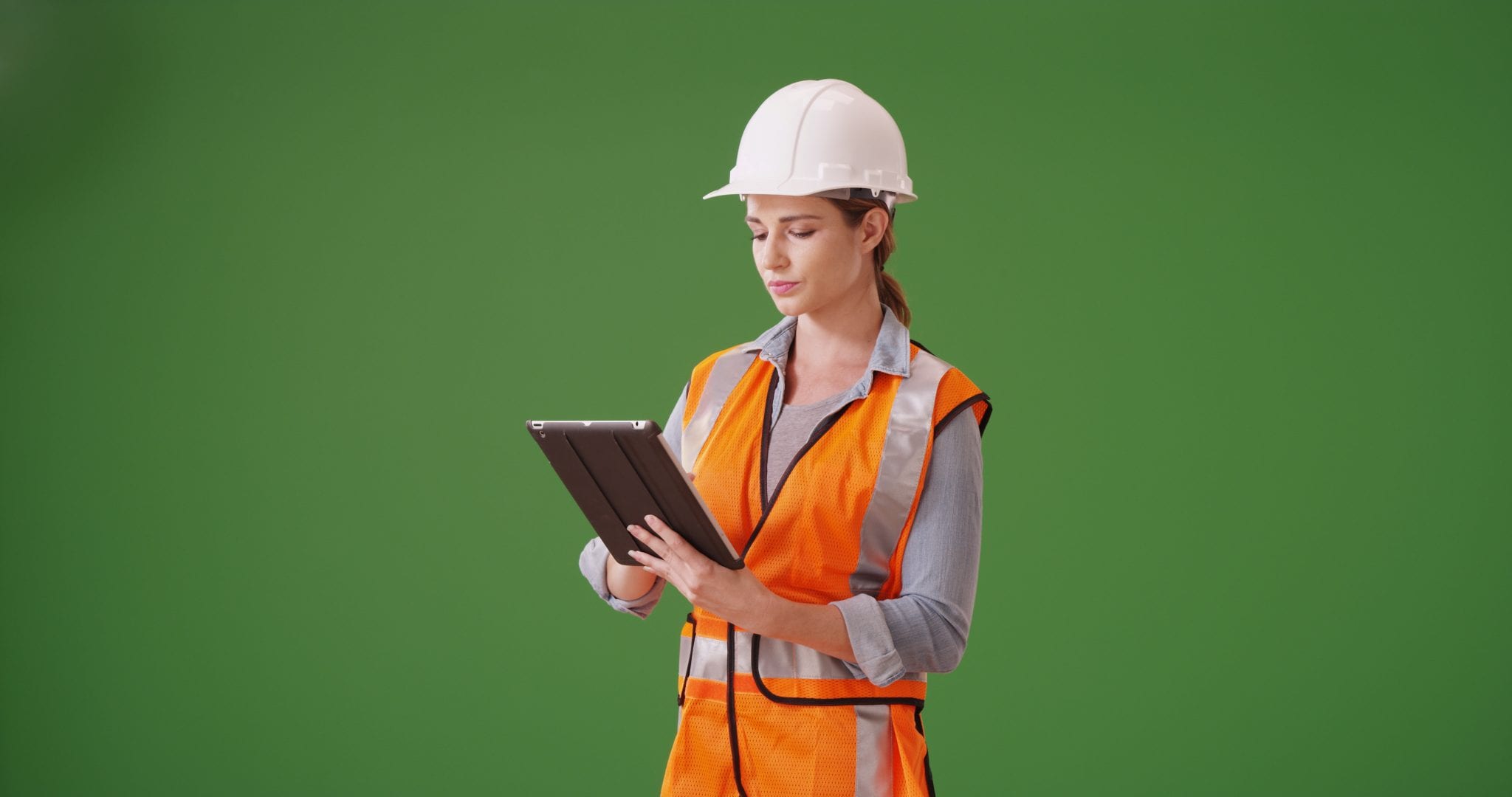 Young woman in white hat viewing a tablet screen against a green background