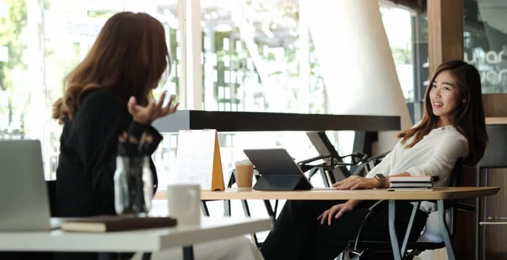 Women brainstorming and talking at their laptops.