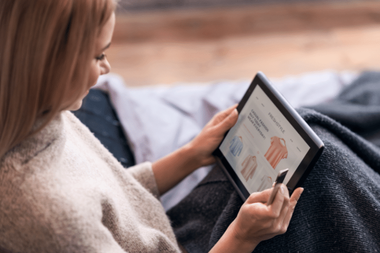 Joyful woman enjoying online shopping in bed